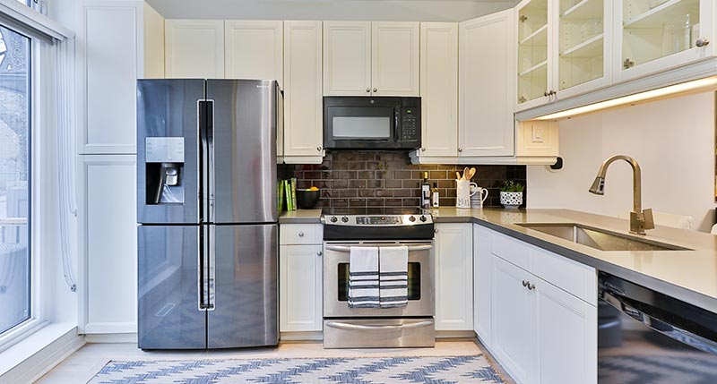 A kitchen with a fridge, oven, and microwave